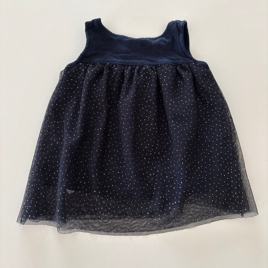A sleeveless navy blue dress with a sheer tulle skirt featuring small glittery polka dots, laid flat on a light off-white background.