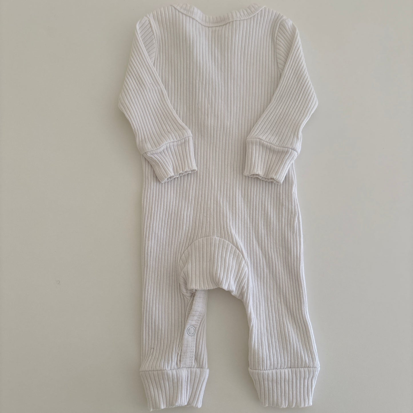 White ribbed baby onesie on a light gray background