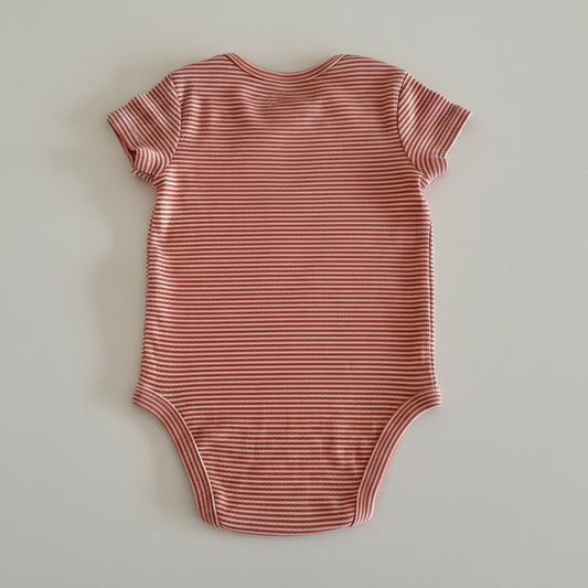 orange and white striped baby bodysuit on light background