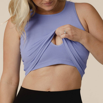 Woman wearing a purple sports bra and black leggings against a beige background