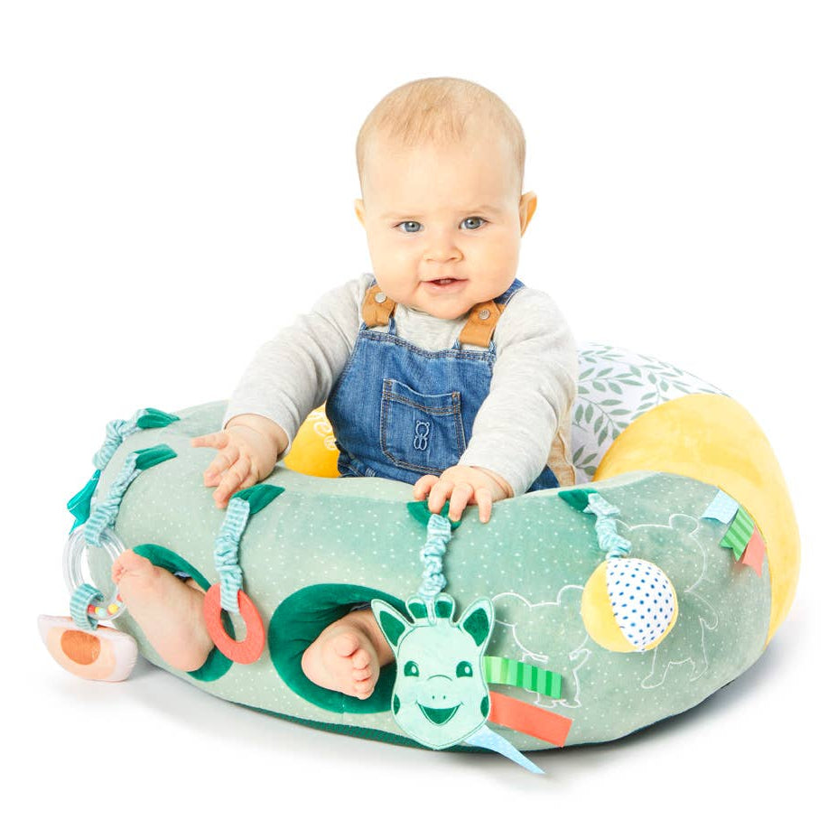 Baby sitting in a colorful toy seat with various textures and patterns on a white background