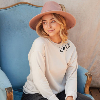 Light tan (Heather dust) colored crewneck sweatshirt with XOXO written on the neckline in eco-friendly, black ink