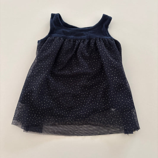 A sleeveless baby dress in navy blue with a sheer, dotted tulle skirt, laid flat on a light beige background.