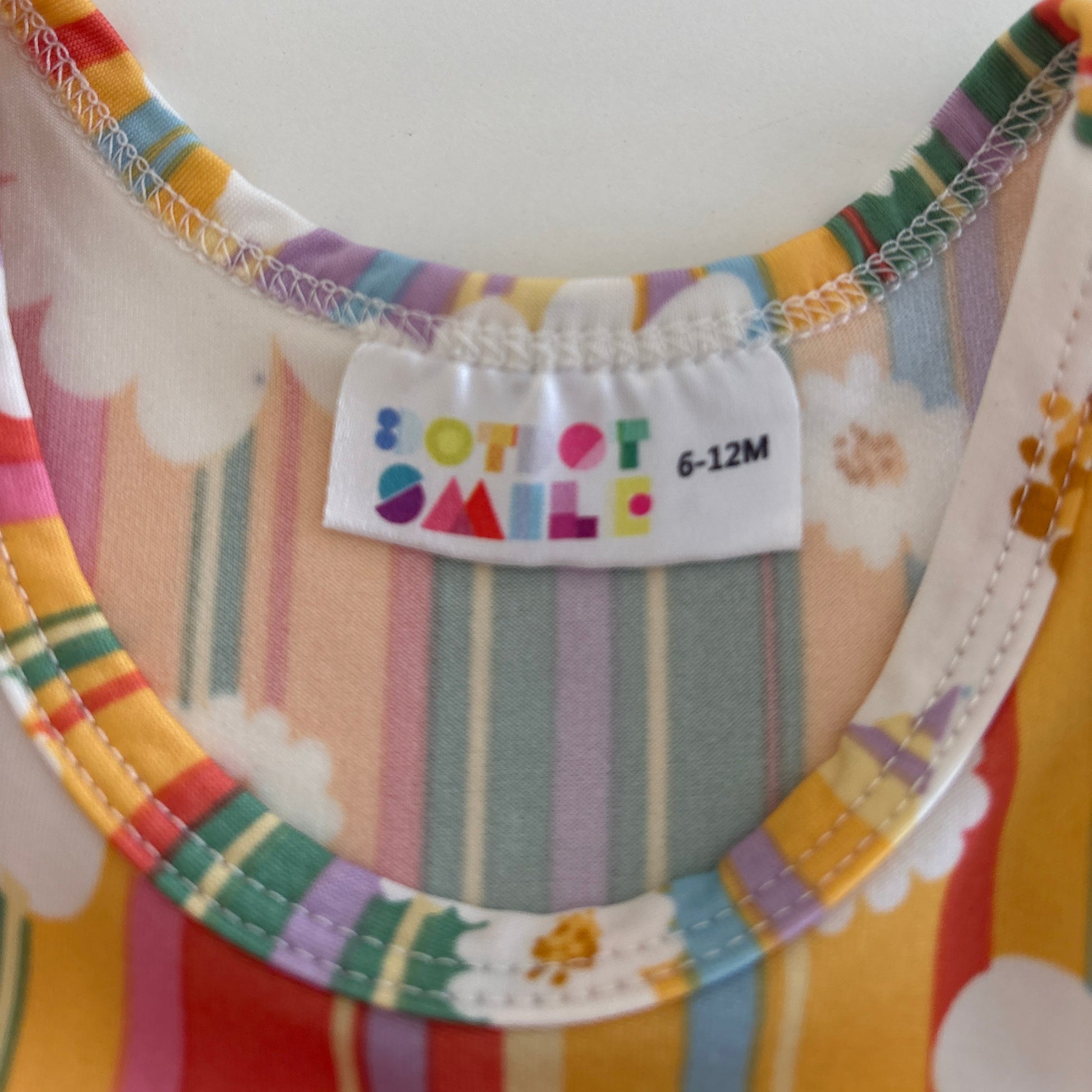 Colorful baby bib with floral patterns and a brand label on a white background