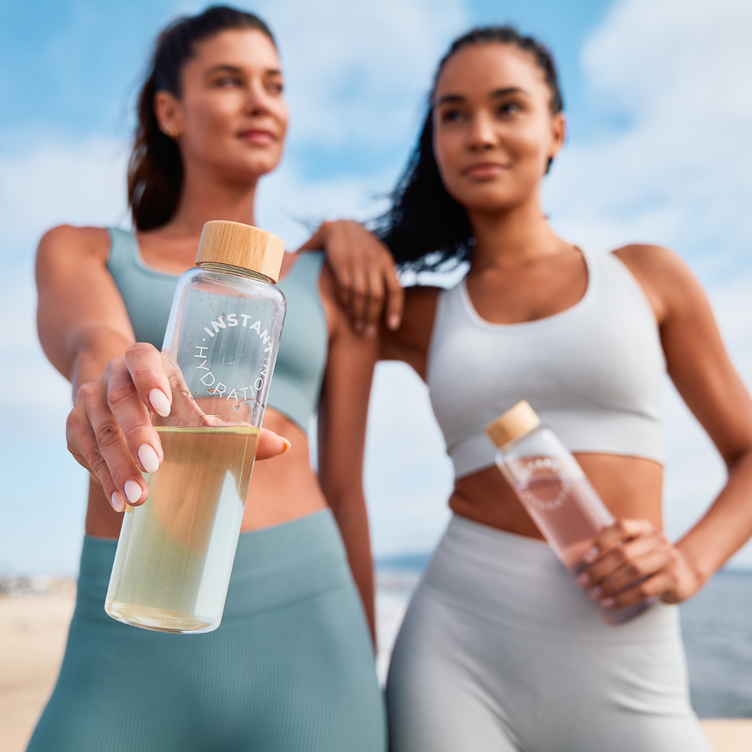 Two women holding water bottles with a clear background