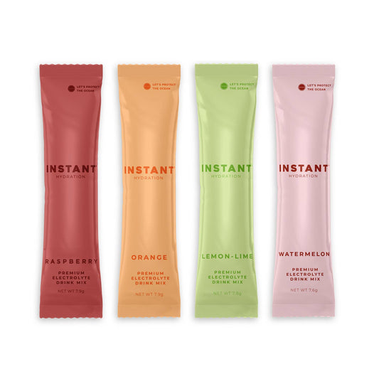 Four instant drink mix packets in different flavors on a white background