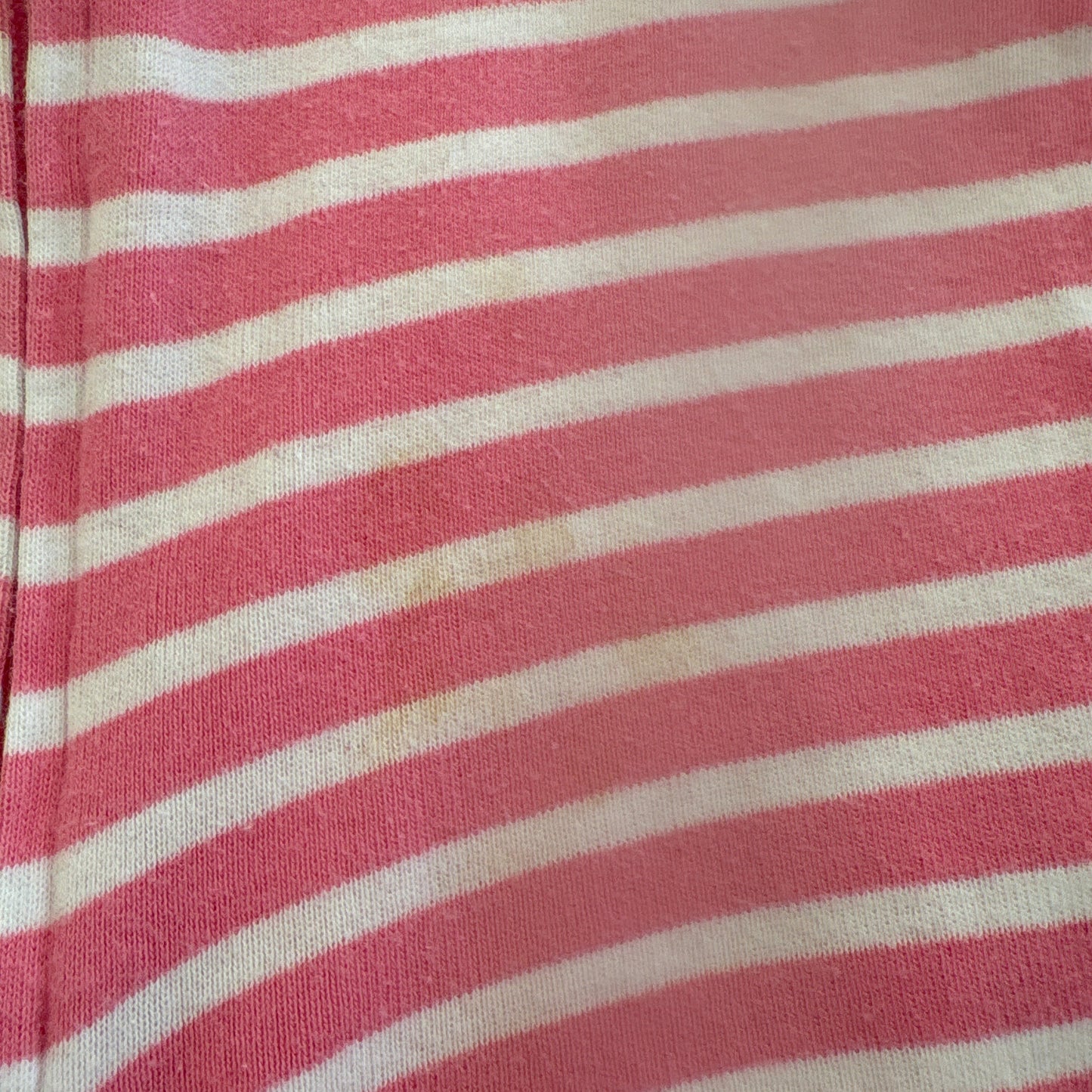 Close-up of pink and white striped fabric to show small stain