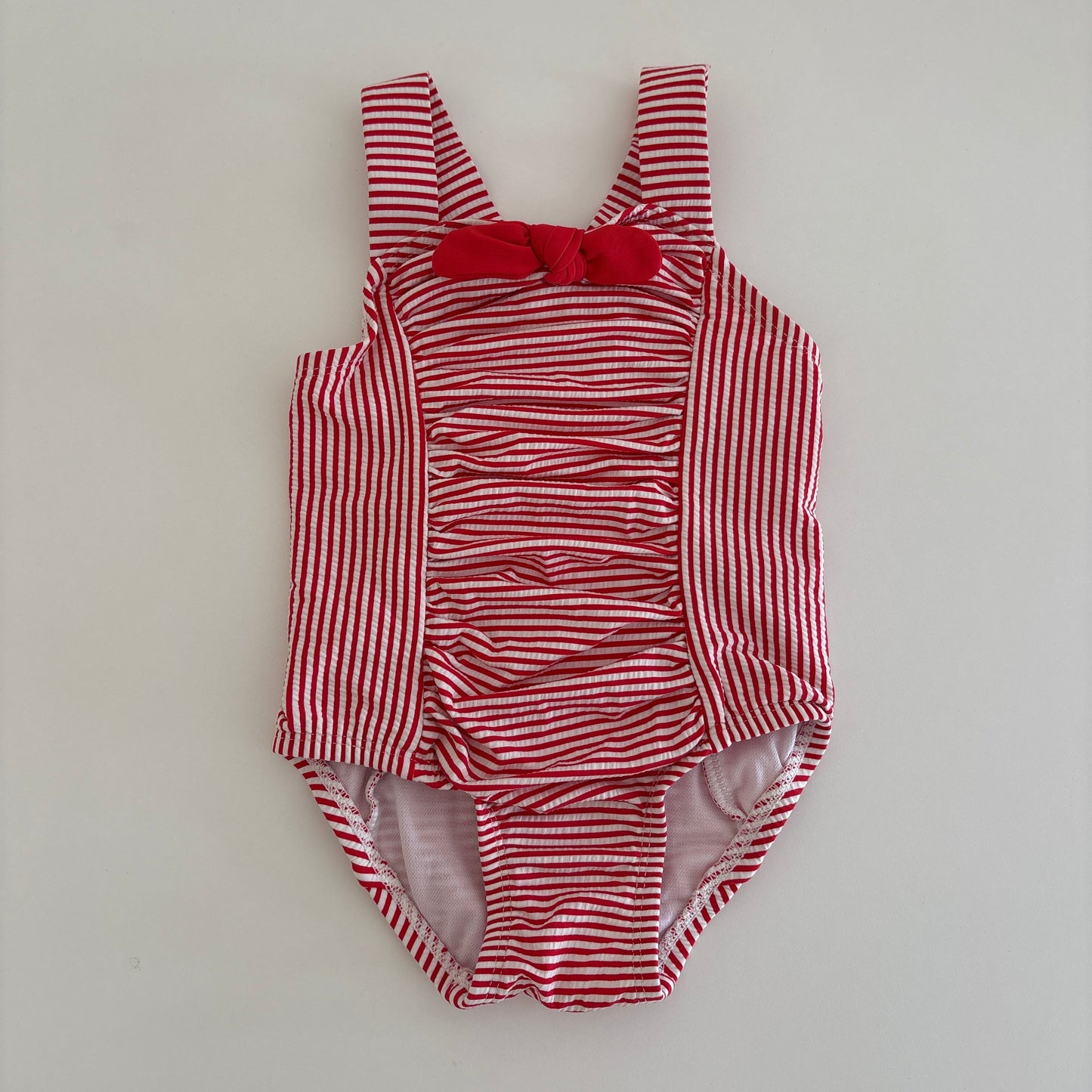 Red and white striped baby outfit on a light gray background