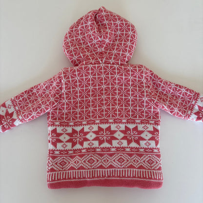 A pink and white patterned knit hooded sweater laid flat on a light off-white background.
