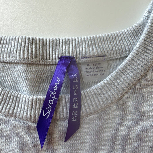 Gray sweater with a purple tag on a light gray background