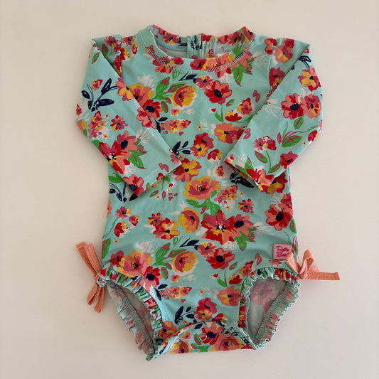 Floral-patterned baby swimsuit on a light beige background