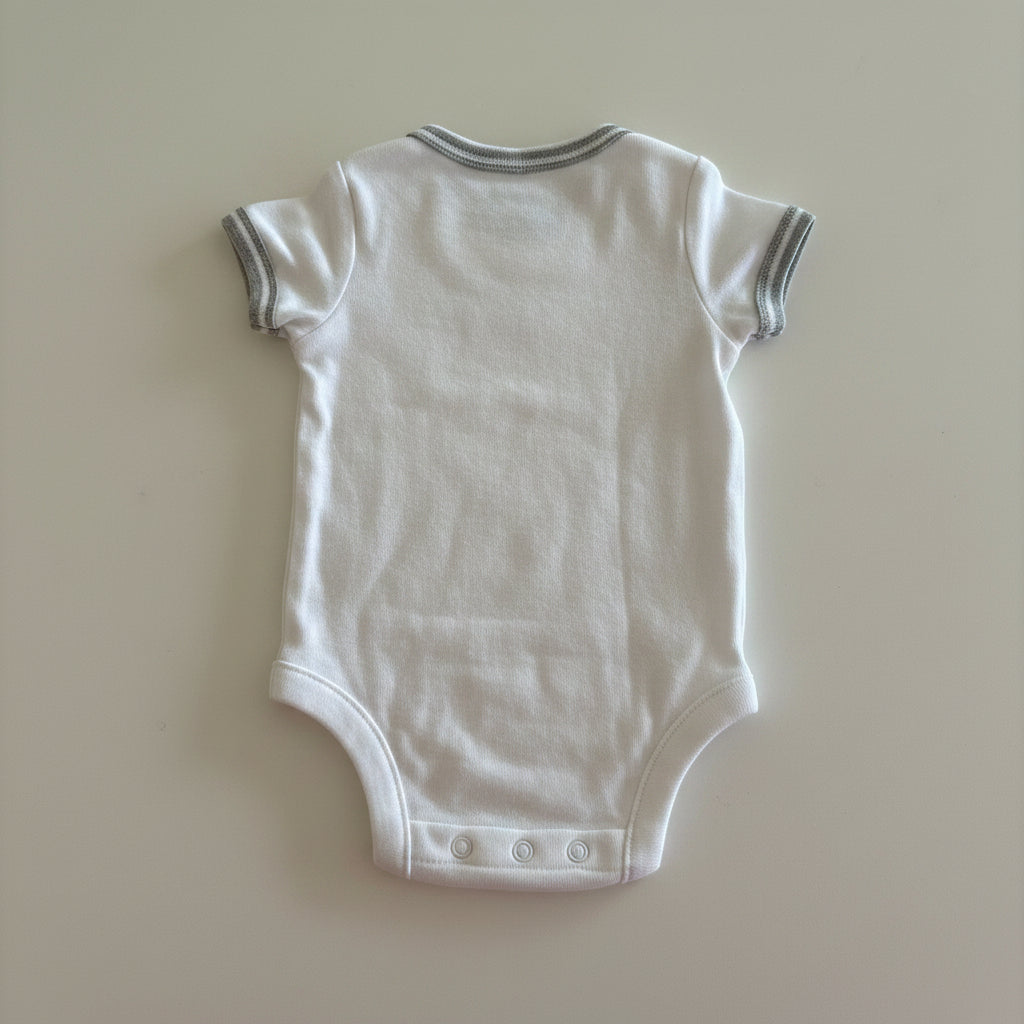 White baby onesie on a beige background
