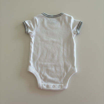 White baby onesie on a beige background