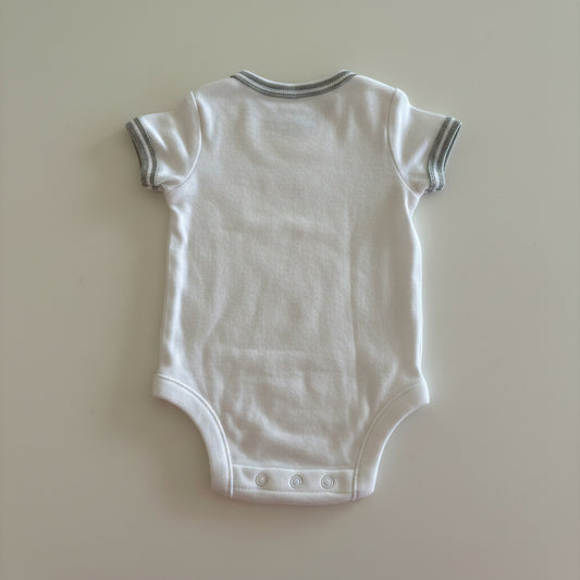 White baby onesie on a beige background
