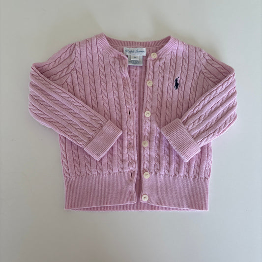 A light pink cable-knit cardigan sweater with a button-up front, laid flat on a light beige background.