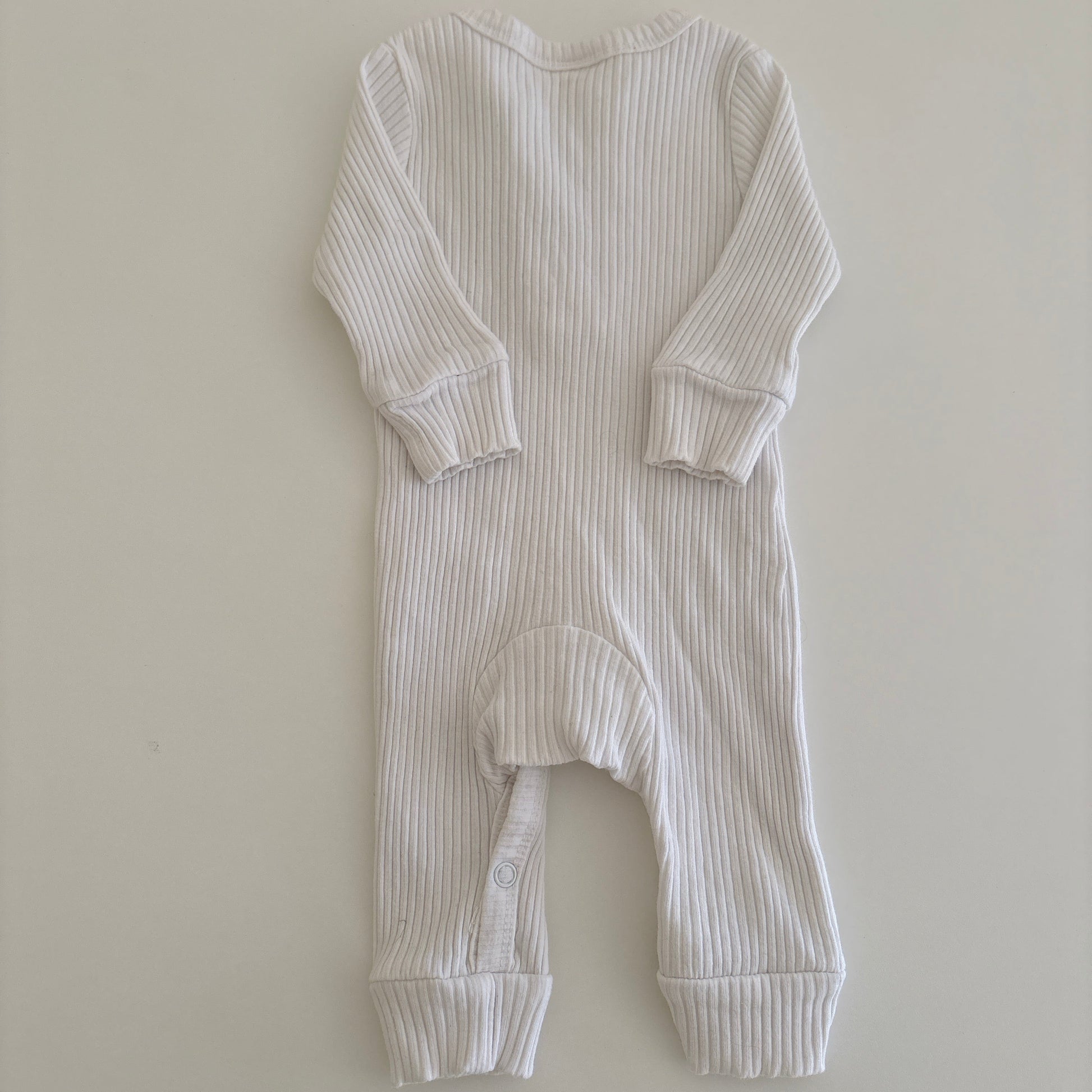 White ribbed baby onesie on a light gray background
