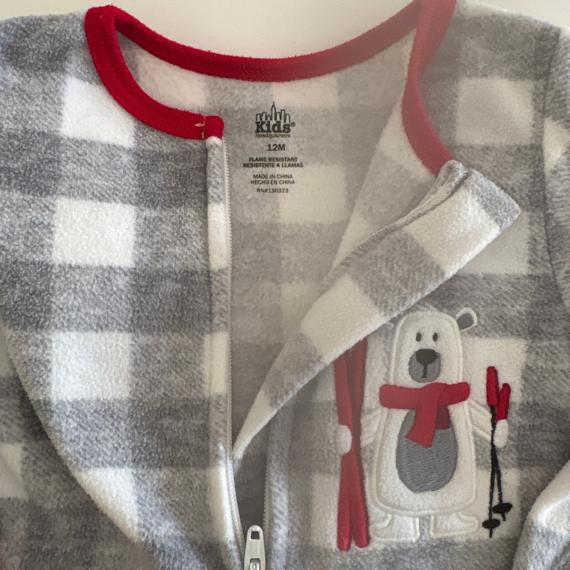 Gray and white checkered baby outfit with red trim on a light background