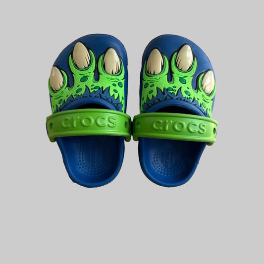 Pair of blue and green Crocs sandals on a gray surface