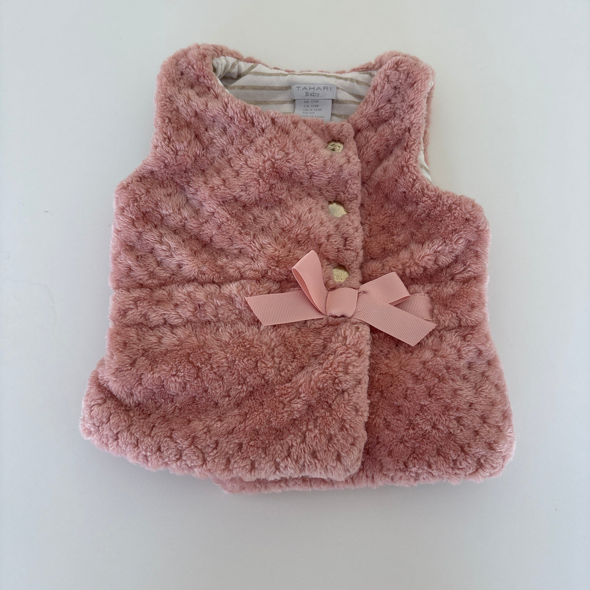 A dusty pink textured knit pet sweater with a matching pink ribbon bow and decorative buttons, laid flat on a white background.