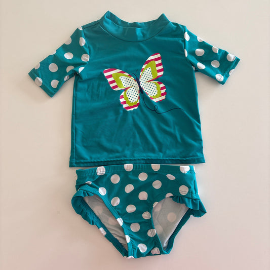 Teal children's swimsuit with polka dot pattern on a beige background