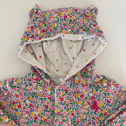 A children's hooded jacket or coat with a dense multicolor floral print on a white base, featuring bear-ear shaped hood details and a light cream inner lining with small colorful dots.