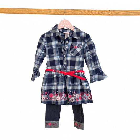 Plaid dress with floral accents on a hanger against a beige wall