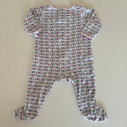 A baby long-sleeve footed sleeper with a dense butterfly print on a white background, laid flat on a beige surface.
