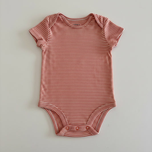 orange and white striped baby onesie on a light gray background