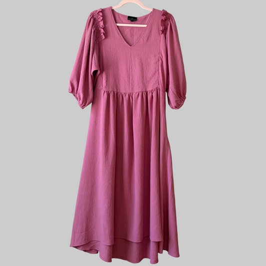 A pink midi nursing dress with short puffed sleeves, a V-neckline, and a zipper at the front for nursing access. The dress is displayed on a hanger against a plain background.