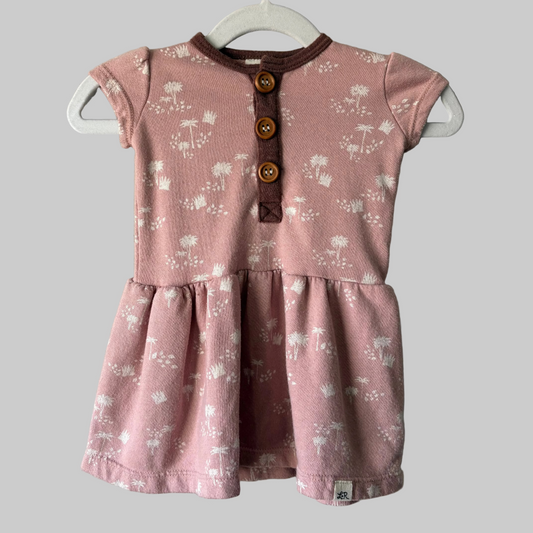 A short sleeve pink baby dress with a floral pattern, displayed on a hanger.