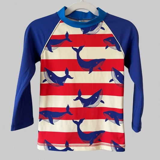 A long sleeve swim top for kids featuring red and white stripes with blue whale patterns, and solid blue sleeves.
