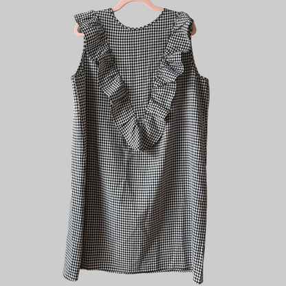 A sleeveless nursing dress in black and white gingham with a hidden zipper, displayed on a hanger