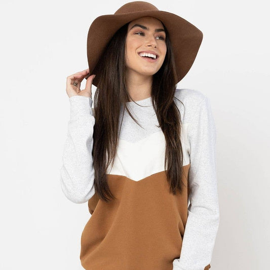 Woman wearing a brown and white sweater with a brown hat on a plain background