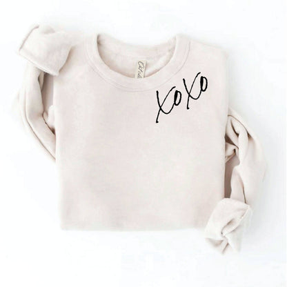 XOXO on neckline of light crewneck sweatshirt
