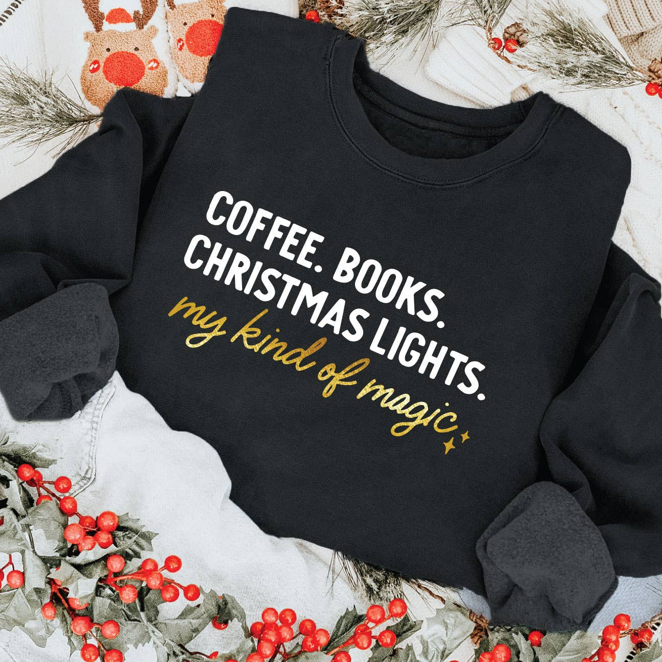 Black sweatshirt with text 'Coffee. Books. Christmas lights. My kind of magic.' on a festive background.